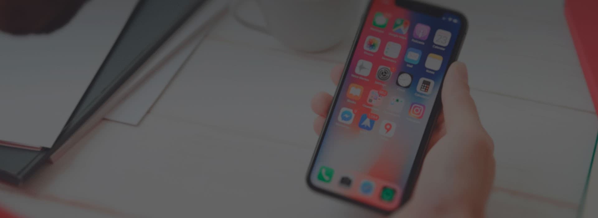 Hand holding an iPhone with iOS home screen